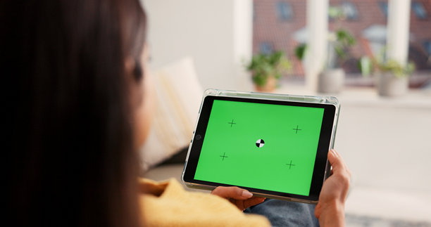 女性，在家里使用带绿屏的平板电脑进行广告、研究或营销应用。背视图，女性人物或用户使用技术显示屏在模拟空间中进行在线娱乐，在家中。图片下载
