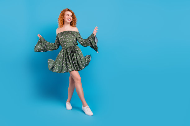 年轻迷人的女孩全身照，带着快乐积极的笑容，梦幻的眼神，旁边有空白空间，孤立在蓝色背景上图片下载
