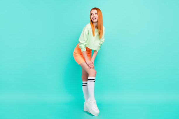 迷人、梦幻的年轻女子身穿短裙，表情空洞地看向远方，孤立在青色背景上，全尺寸照片图片下载