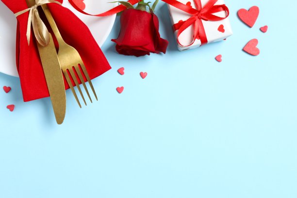 情人节概念。蓝色背景上的餐具、红玫瑰、礼品盒和纸屑的俯视照片，留有空白空间图片下载
