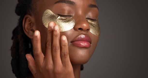 美容、眼罩和面部护理，黑人女性在工作室空间进行化妆品或皮肤病学治疗。金色产品和护肤品涂抹在非洲模特脸上，在灰色背景下孤立，用于抗衰老治疗。图片下载