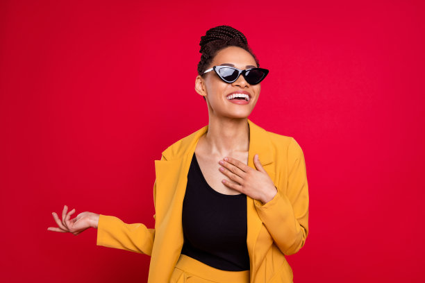 照片：一位戴着眼镜、穿着黄色开衫的滑稽时髦女士，背景是鲜艳的红色图片下载