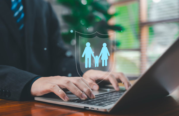 一位商务专业人士正在使用笔记本电脑打字，屏幕上显示一个发光的家庭保护盾图标，象征着家庭保险、数字安全、安全服务、数据保护和现代在线防护。图片下载