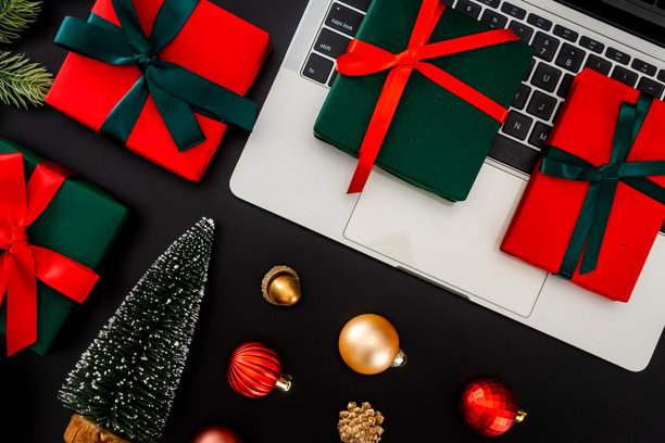 俯视视角，圣诞风格的工作空间，带有笔记本电脑和装饰性礼物，背景为黑色。自由职业和节日工作概念。图片下载