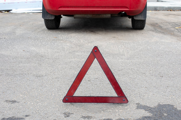 红色轿车后方沥青路上的红色警示三角。道路安全，车辆故障，应急设备。真实照片图片下载
