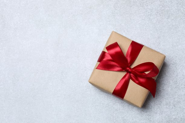 俯视角度拍摄的，灰色背景上方一个小巧亮眼的礼品盒的特写照片图片下载