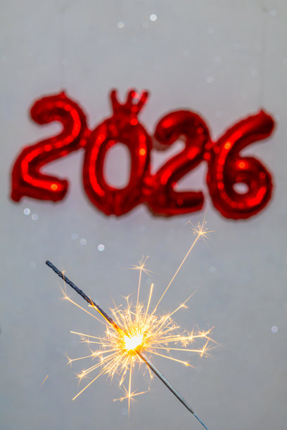 节日新年照片，前景是明亮的闪光鞭炮，背景是模糊的红色箔2026气球和绿色背景图片下载