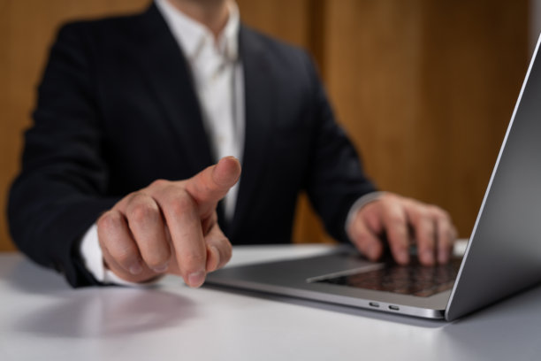 商务人士在办公室环境中工作会议期间，用手指着屏幕使用笔记本电脑，展示了现代科技互动概念。图片下载