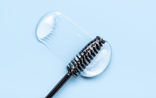 特写照片，透明的眉毛和睫毛精华液，质地光滑有光泽，背景为蓝色图片下载
