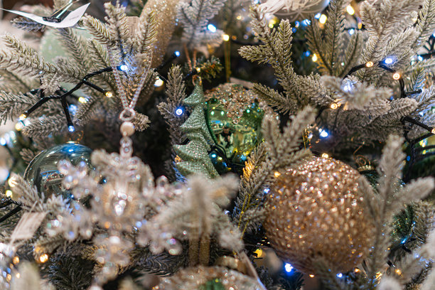 一张专业拍摄的图片，展示了一棵华丽的、以白色和银色为主的圣诞树，背景模糊。树上装饰着许多灯饰和金色饰品。图片下载