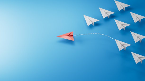 不同的商业概念。新想法。纸艺风格。创意想法。红色的领头飞机，在白色飞机群中脱颖而出。蓝色背景上的 3D 渲染。图片下载
