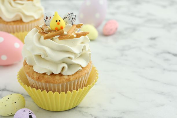 美味的复活节杯子蛋糕，配有香草奶油和糖果，放在白色大理石桌上，留有文字空间图片下载