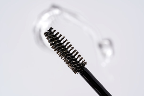 白色背景下，用于眉毛和睫毛的精华凝胶笔触，旁边放着一把刷子图片下载