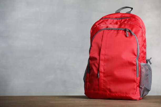 灰色背景下的木桌上的红色背包。留有文字空间图片下载