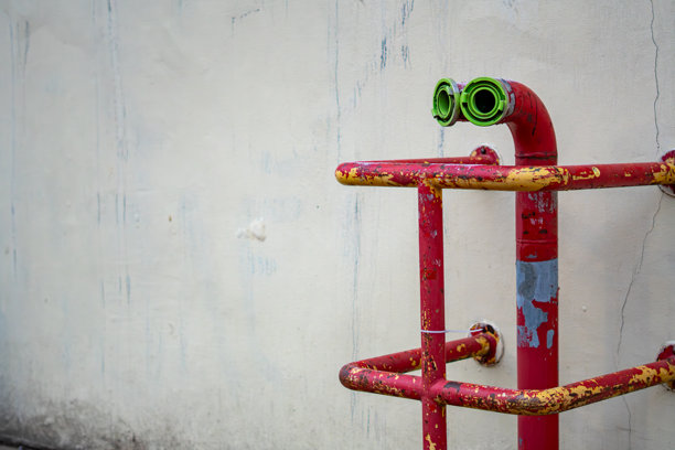 安装在墙壁上的带绿色接头的红色消防管道，构成公共空间工业城市基础设施的细节图片下载