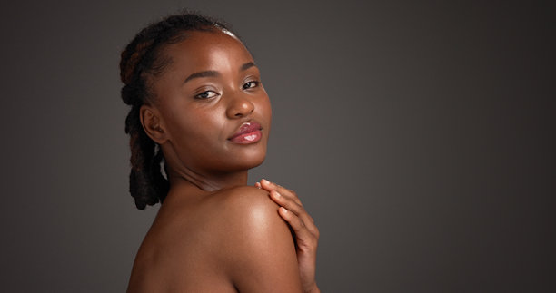 肩部特写，黑人女性在工作室进行的护肤、自我护理和皮肤科护理肖像。留有样机空间，深色背景，模特拥有天然美貌，展现健康和美容，肌肤焕发光彩。图片下载