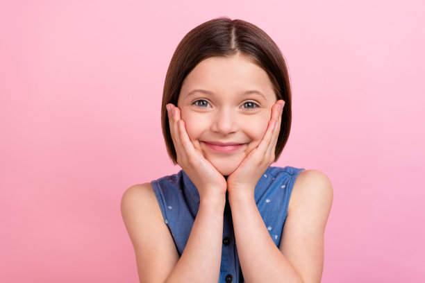 照片肖像：快乐微笑的女学生用手掌触摸脸颊，孤立在粉彩色背景上图片下载