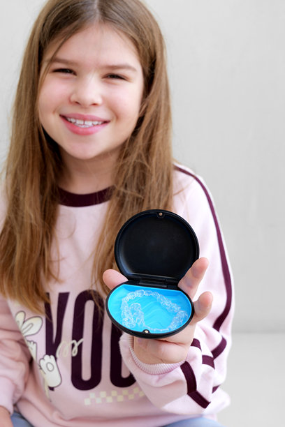 少女展示透明牙套小盒子，舒适的牙齿矫正方案和日常口腔护理。明亮自然的图像，非常适合推广儿童和青少年牙套的诊所图片下载