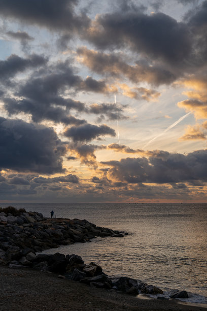 清晨海岸的独照，日出时分海岸线上摄影师的剪影，孤独的摄影师在黎明时分用相机和三脚架在海边拍摄日出照片图片下载