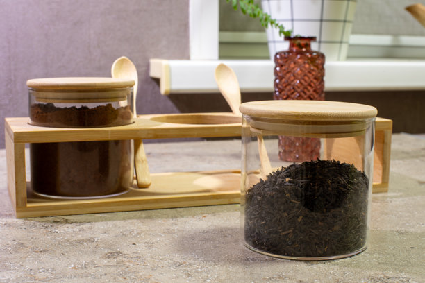 舒适厨房里的木制收纳架上放着装有茶叶的圆形玻璃罐和装有咖啡的罐子。带木盖的玻璃香料罐。真实照片图片下载