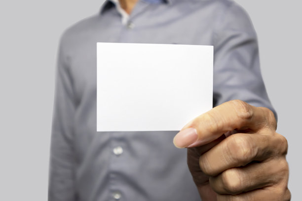 一位穿着灰色衬衫的商人伸出一张白纸，可用于插入图片或文字进行平面设计。图片下载