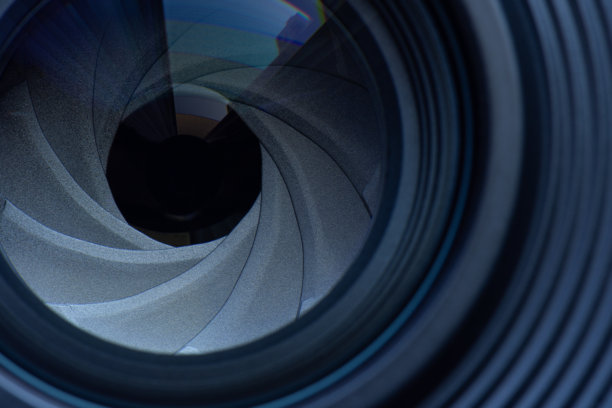 微距镜头，老式相机镜头光圈的隔膜，带有暖色调的焦外成像。选择性聚焦，景深浅。复古色调过滤。黑色背景上特写的光线反射照片或视频相机镜头。图片下载