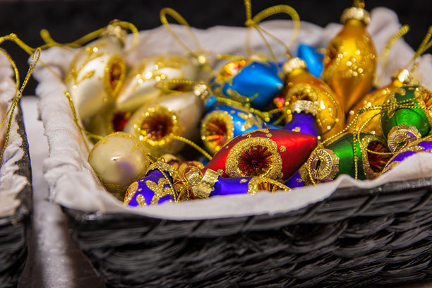 色彩缤纷的手工圣诞装饰球，装在节日市场篮子里。充满活力的手绘圣诞装饰球，装在市场篮子里，闪耀着金色、蓝色、绿色和紫色。图片下载