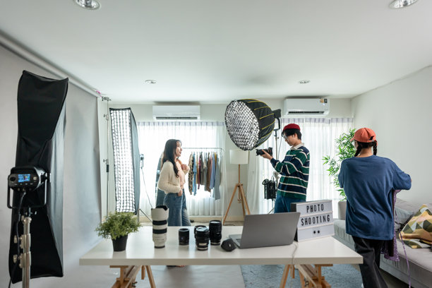 亚洲摄影师在摄影棚拍摄带有背景的女性模特。一位有魅力的专业摄影师运用技巧拍摄精美照片，用于广告或电影。图片下载