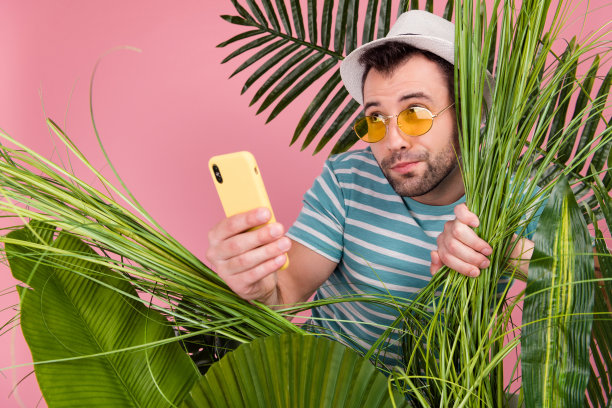 城市博主身穿条纹T恤，在异国风光自然景点旅行，孤立在粉色背景上图片下载