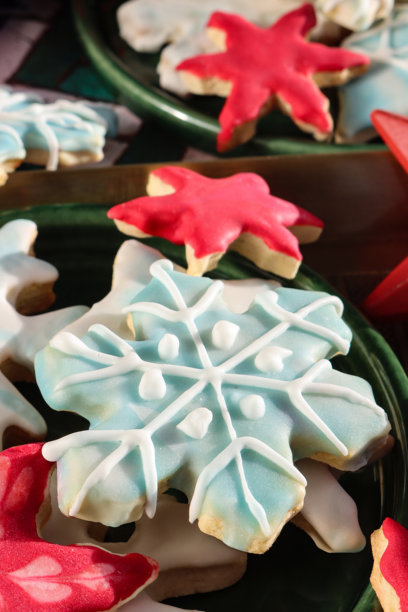全画幅图片，展示一个托盘，里面装着装有自制圣诞美食的绿色盘子，包括皇室糖霜覆盖的糖饼干、雪花图案的饼干，以及红色、白色和淡蓝色的雪花，俯视角度。图片下载