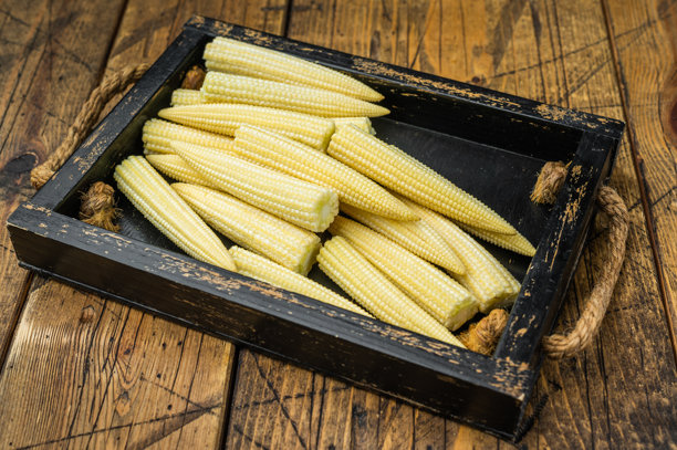 乡村餐桌上木箱里未煮过的嫩玉米，旁边放着百里香，俯视角度，适合自然美食摄影和素材使用图片下载