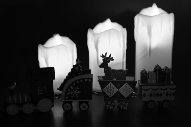 燃烧的蜡烛背景下的玩具火车。黑白照片。图片下载