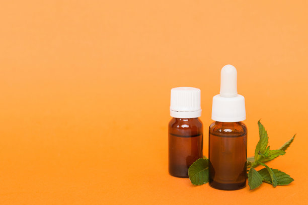 玻璃瓶装的天然薄荷精油。有机化妆品，含有薄荷草本精华，置于彩色背景上。图片下载