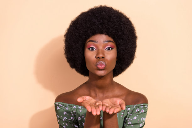 年轻迷人的非洲裔女性照片，噘着嘴，送出飞吻，浪漫情人节，孤立在米色背景上图片下载