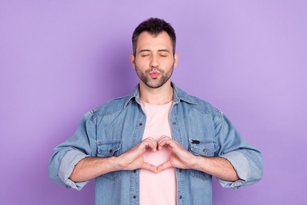 照片肖像：深棕色头发的男人噘嘴送飞吻，背景为柔和的紫色图片下载