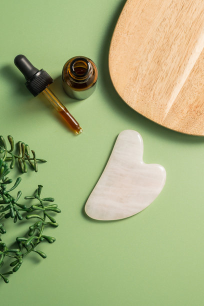 玫瑰石英刮痧工具和面部按摩油瓶，美容抽象照片。俯视图片下载