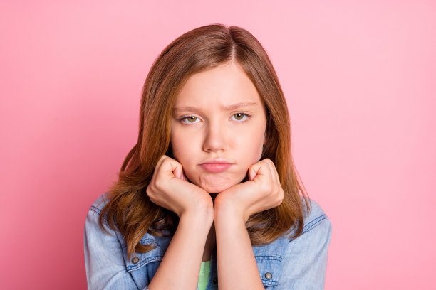 照片肖像：心情糟糕、脾气暴躁、不高兴的女孩，孤立在粉彩粉色背景上图片下载