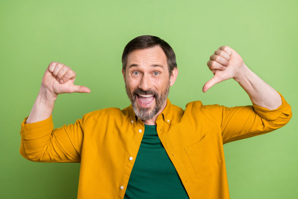 照片：年轻快乐自豪的男人，竖起手指指向自己，面带微笑，像个赢家，在绿色背景前图片下载