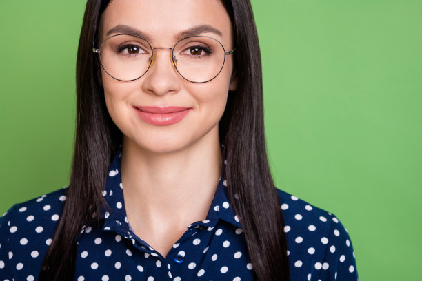 特写照片：戴眼镜、穿着圆点衬衫的可爱棕色头发女老板，孤立在绿色背景上图片下载