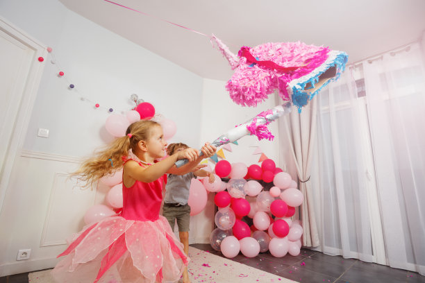生日派对上，一个小女孩正在敲打独角兽形状的生日宾果。这张图片充满动感。图片下载