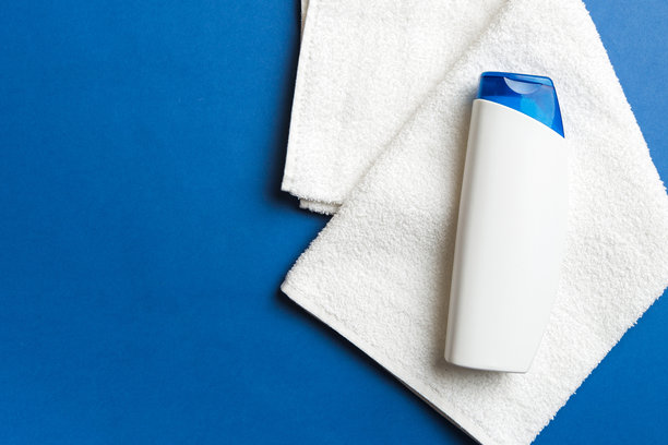 毛巾放在彩色桌子上的化妆洗发水瓶模型。浴室背景，手部和身体护理的洗浴用品。图片下载