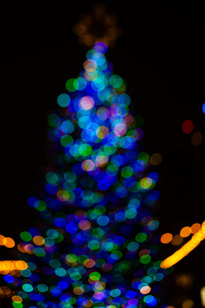 圣诞树节日背景，带有雪花顶饰。装饰精美的圣诞树。夜晚模糊的圣诞树。节日圣诞树，饰有灯饰和花环。第一颗星点亮。图片下载
