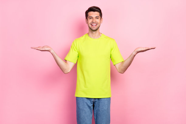 身穿亮色T恤的棕色头发男子的照片肖像，他正在比较空的空间，背景是孤立的粉彩色粉红色图片下载