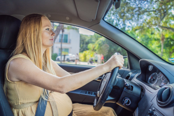 孕妇在车内系着安全带驾驶。一位自信而有能力的孕妇握住方向盘，谨慎而坚定地驾驶，开启了母性之旅。图片下载