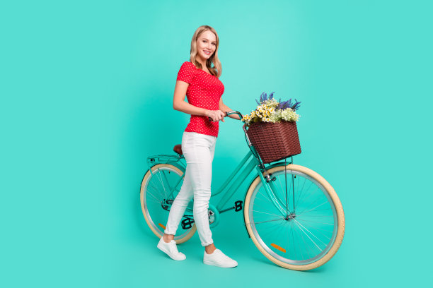 女子全身照，牵着复古自行车和花篮，背景是鲜艳的青色图片下载