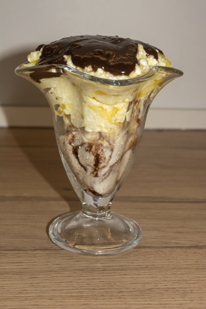 玻璃杯里的甜点，配有冰淇淋、水果和巧克力糖浆图片下载