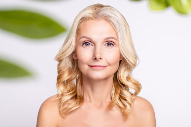 照片：一位有魅力的年长女性，面带愉悦的笑容，接受美容整形手术，背景为灰色图片下载