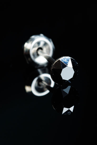 银耳环的宏观照片，上面镶嵌着宝石，背景为黑色孤立。焦点选择。图片下载