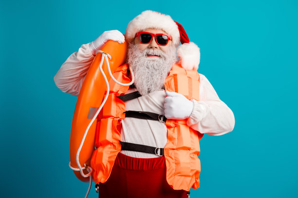 圣诞老人身穿亮橙色救生衣，手持礼物，背景为蓝色，面带笑容，供圣诞节素材使用图片下载