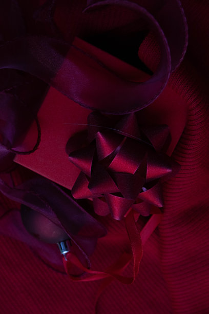 一张近距离拍摄的精美礼品包装照片，色调为浓郁的红色和酒红色。图片下载
